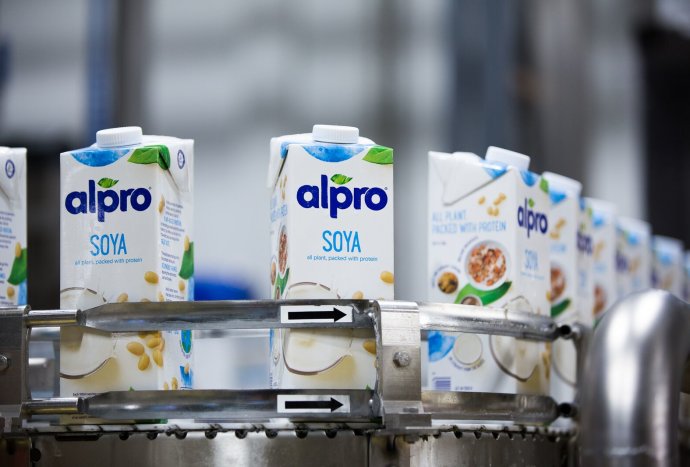Cartons of Alpro Soya beverage on conveyer belt in processing facility.